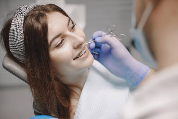 female-patient-with-braces-has-dental-examination-dentist-office-stomatologist-wearing-blue-gloves